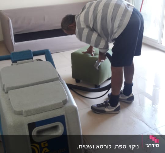 אדם מנקה ספה עם מכונת ניקוי מקצועית